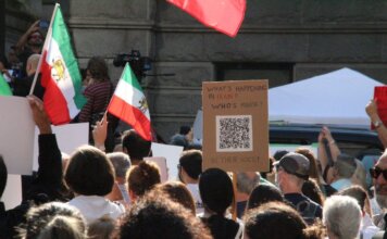 Канада ввела новые санкции против пяти физических лиц и пяти организаций Ирана Crowd demonstrating in Vancouver with Iranian flags advocating for human rights and freedom.