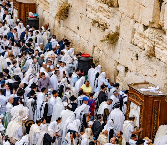 Crowds of people in prayer at the Western Wall, Jerusalem, during a religious event.