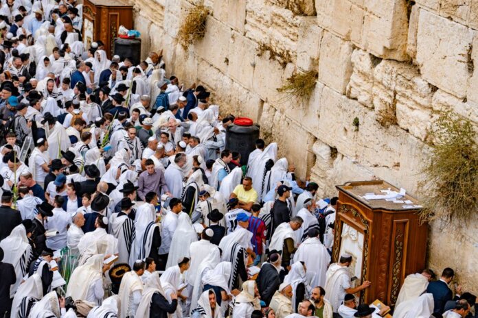 Crowds of people in prayer at the Western Wall, Jerusalem, during a religious event.