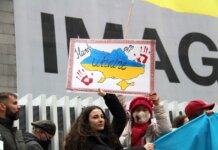 Demonstrators rally for Ukraine in Vancouver, holding signs and flags during a peaceful protest.