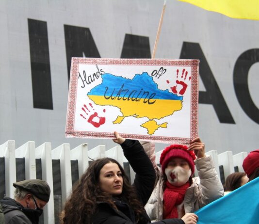 Demonstrators rally for Ukraine in Vancouver, holding signs and flags during a peaceful protest.