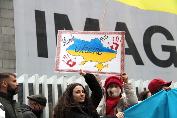 Demonstrators rally for Ukraine in Vancouver, holding signs and flags during a peaceful protest.