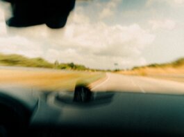 Dynamic blurred image from a vehicle's windshield capturing a rural road in motion.