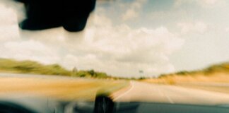 Dynamic blurred image from a vehicle's windshield capturing a rural road in motion.