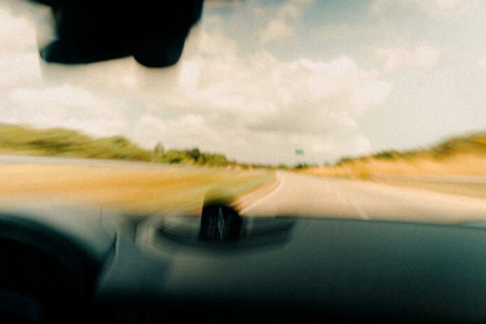 Dynamic blurred image from a vehicle's windshield capturing a rural road in motion. Dynamic blurred image from a vehicle's windshield capturing a rural road in motion.
