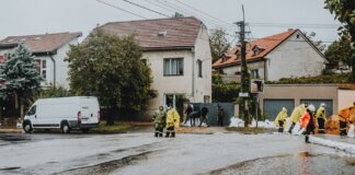 Emergency response team tackles flooding in a residential neighborhood with sandbags and preparation.