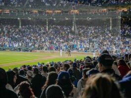 Energetic scene of a nighttime baseball game with a packed stadium crowd.