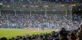 Energetic scene of a nighttime baseball game with a packed stadium crowd.