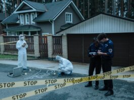 Forensic team investigates suburban crime scene with police officers and evidence markers.