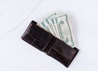 Консерваторы: бездомность в Онтарио выросла на 23% за три года From above of black leather wallet with pockets filled with heap of dollar banknotes on white table