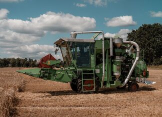 Green combine harvester operating in a wheat field in Hohenhorn, Germany under a clear blue sky.