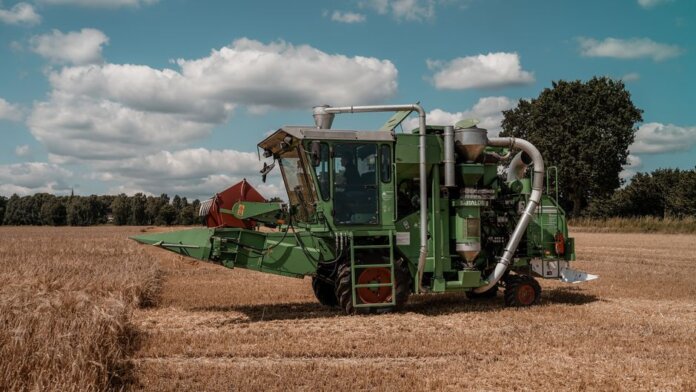 Green combine harvester operating in a wheat field in Hohenhorn, Germany under a clear blue sky. Green combine harvester operating in a wheat field in Hohenhorn, Germany under a clear blue sky.