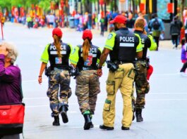 Group of police officers in uniform patrolling a crowded city street on a sunny day.