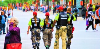 Group of police officers in uniform patrolling a crowded city street on a sunny day.