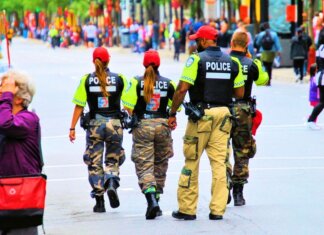 Консерваторы: либералы наймут в КККП лишь 750 полицейских вместо 1000 Group of police officers in uniform patrolling a crowded city street on a sunny day.