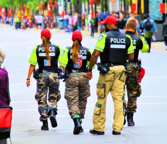 Group of police officers in uniform patrolling a crowded city street on a sunny day.