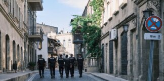 Group of policemen strolling through a historic European city street on a sunny day.