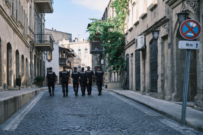 Group of policemen strolling through a historic European city street on a sunny day. Group of policemen strolling through a historic European city street on a sunny day.