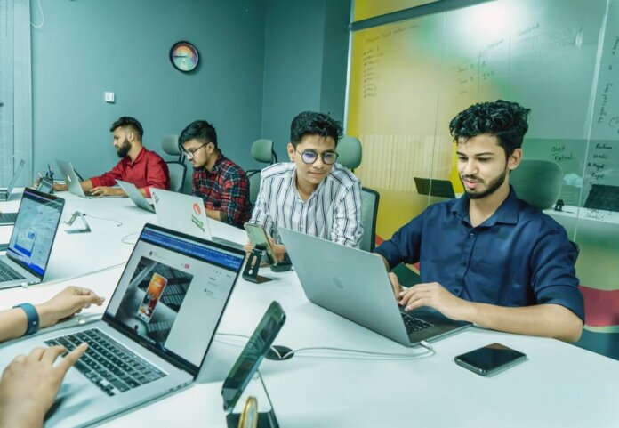 Group of young professionals working together in a modern office setting, using laptops and technology. Group of young professionals working together in a modern office setting, using laptops and technology.