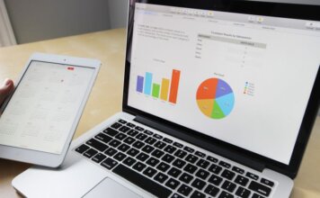 Laptop displaying charts and graphs with tablet calendar for data analysis and planning.