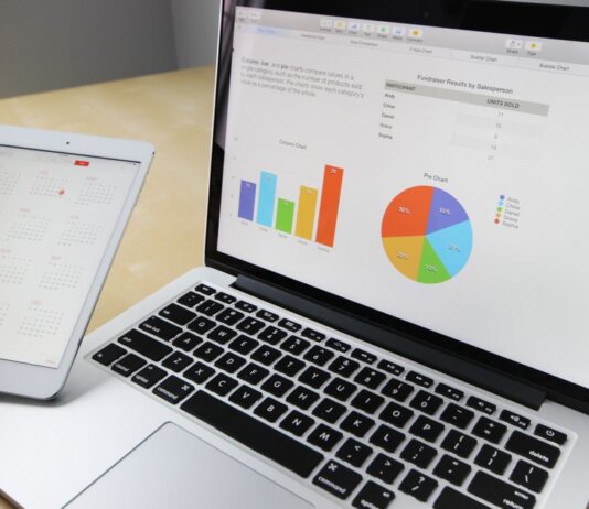 Laptop displaying charts and graphs with tablet calendar for data analysis and planning.