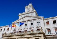Low-angle view of the Municipal Palace with flags in Ferrol, Spain on a sunny day.