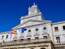 Low-angle view of the Municipal Palace with flags in Ferrol, Spain on a sunny day.