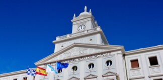Low-angle view of the Municipal Palace with flags in Ferrol, Spain on a sunny day.