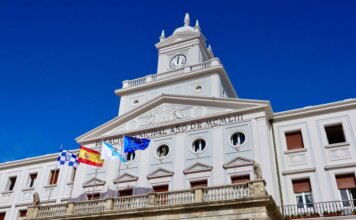 Low-angle view of the Municipal Palace with flags in Ferrol, Spain on a sunny day.