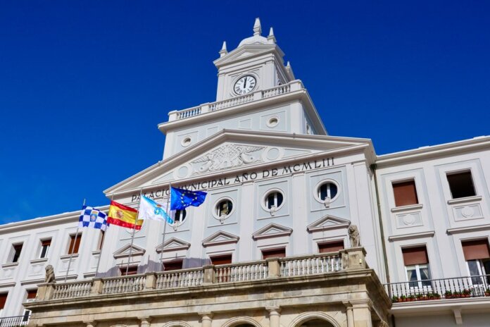 Low-angle view of the Municipal Palace with flags in Ferrol, Spain on a sunny day.