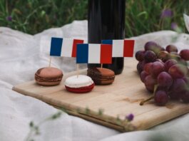 Macarons decorated with French flags on a picnic setup with grapes and wine.