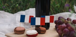 Macarons decorated with French flags on a picnic setup with grapes and wine.