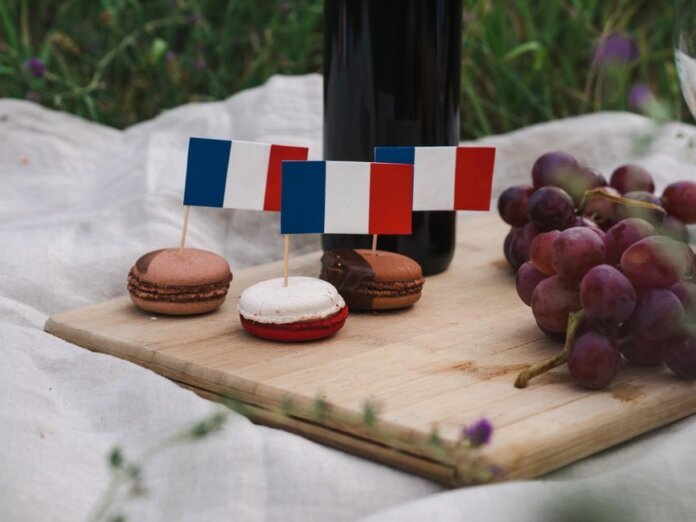 Macarons decorated with French flags on a picnic setup with grapes and wine. Macarons decorated with French flags on a picnic setup with grapes and wine.