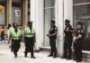 NYPD officers in uniform monitor a busy city street in daytime, ensuring public safety.