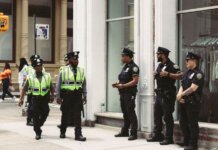 NYPD officers in uniform monitor a busy city street in daytime, ensuring public safety.