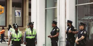 NYPD officers in uniform monitor a busy city street in daytime, ensuring public safety.