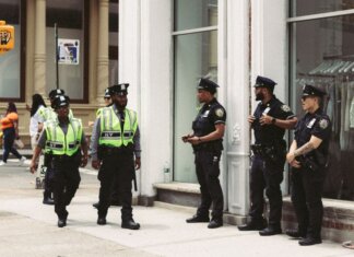NYPD officers in uniform monitor a busy city street in daytime, ensuring public safety.