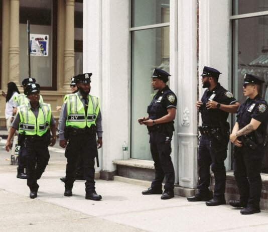 NYPD officers in uniform monitor a busy city street in daytime, ensuring public safety.