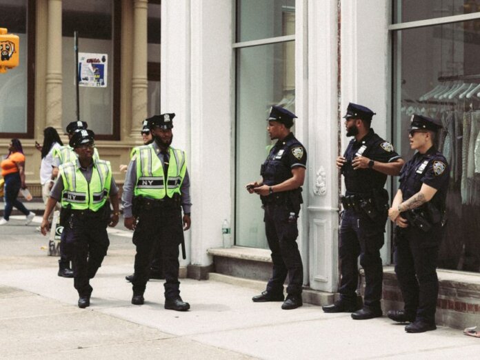 NYPD officers in uniform monitor a busy city street in daytime, ensuring public safety. NYPD officers in uniform monitor a busy city street in daytime, ensuring public safety.