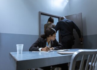 Преступность подрывает бизнес малых предприятий по всей Канаде Police officer escorting suspect as lawyer observes during interrogation.