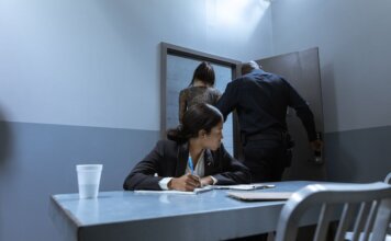 Преступность подрывает бизнес малых предприятий по всей Канаде Police officer escorting suspect as lawyer observes during interrogation.