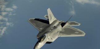 Powerful military aircraft soaring against a calm blue sky.