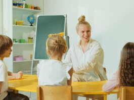 Teacher engaging with preschool children in a colorful classroom setting.