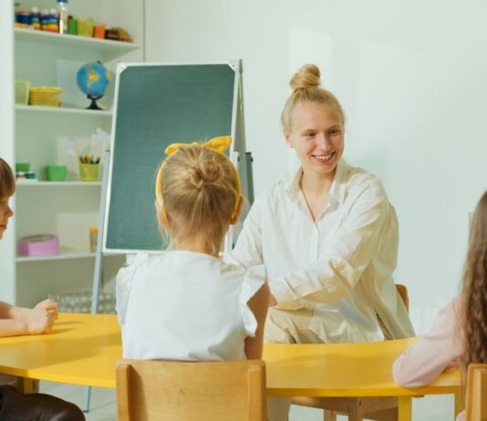 Teacher engaging with preschool children in a colorful classroom setting.
