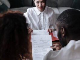 Three people reviewing documents in an office setting, focusing on adoption paperwork.