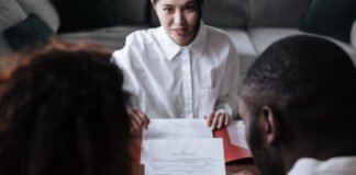 Three people reviewing documents in an office setting, focusing on adoption paperwork.