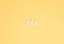 Three white capsules on a vibrant yellow background, symbolizing healthcare and medication.