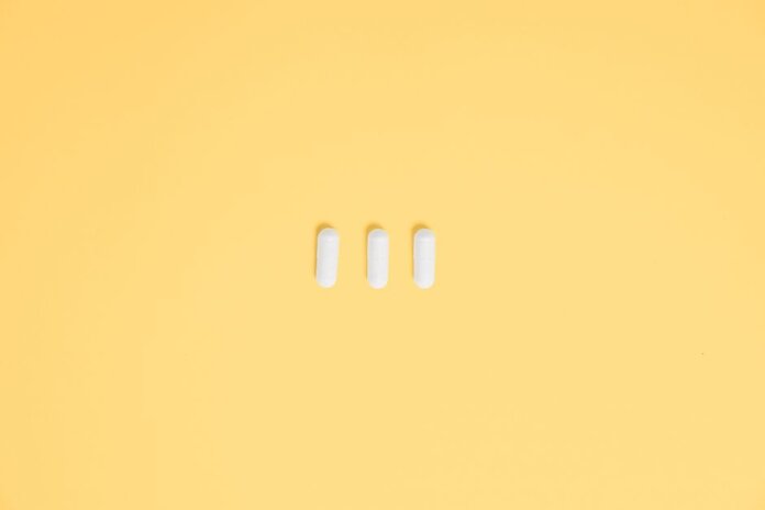 Three white capsules on a vibrant yellow background, symbolizing healthcare and medication. Three white capsules on a vibrant yellow background, symbolizing healthcare and medication.