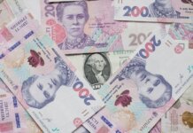 Top view of scattered Ukrainian hryvnia and US dollar banknotes symbolizing wealth.