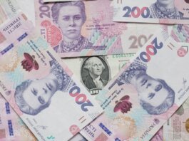 Top view of scattered Ukrainian hryvnia and US dollar banknotes symbolizing wealth.
